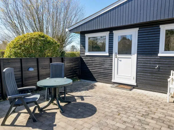 Mørkeblå sommerhus facade med terrasse og havemøbler